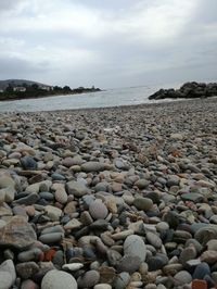 Surface level of pebble beach against sky