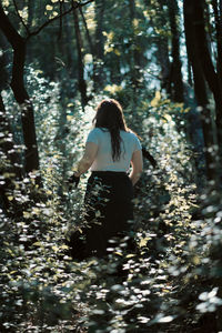 Rear view of woman standing in forest