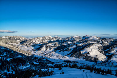 Scenic view of snowcapped mountains against blue sky