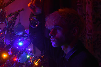 Close-up of young man in illuminated christmas lights
