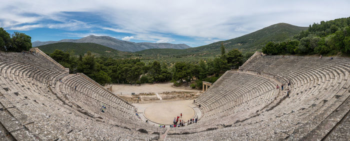 Panoramic view of tourists on mountain against cloudy sky