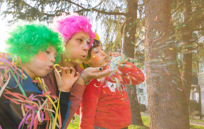 Mother and children blowing streamers while standing in park