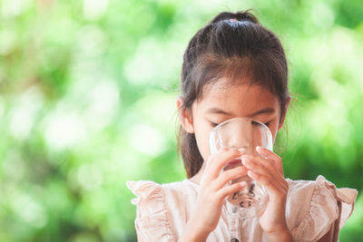 Close-up of girl drinking water from glass outdoors