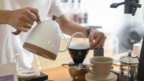 Barista is making drip brewing, filtered coffee with hot water and filter paper in coffee shop .