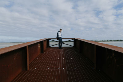 Man standing on bridge against sea