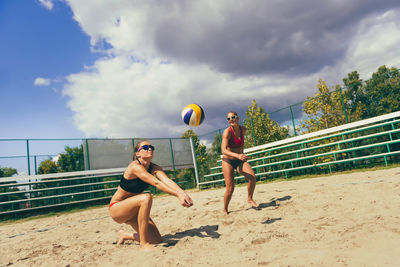 Female friends playing volleyball at beach