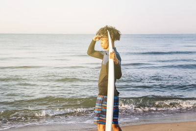 Woman standing at beach against sky