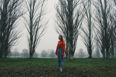Full length of woman standing on field against bare trees