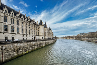 Buildings of the conciergerie in paris by river against sky