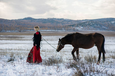 Young woman standing with horse on snow