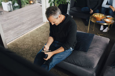 High angle view of man using smart phone while sitting in living room
