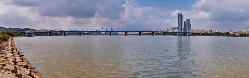 Bridge over river against sky in city