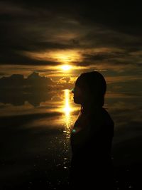 Silhouette woman standing by sea against sky during sunset