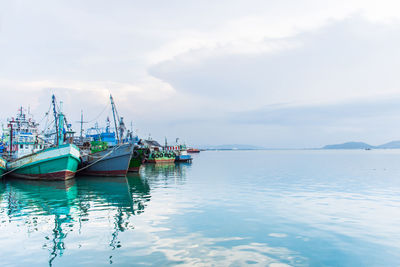 Sailboats moored in sea against sky