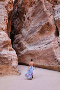 Woman back in long dress walking towards the entrance of the siq of petra, jordan