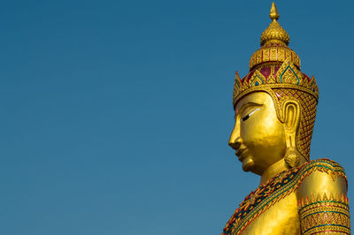 Low angle view of statue against blue sky and building