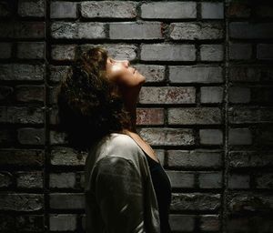 Midsection of woman standing against brick wall