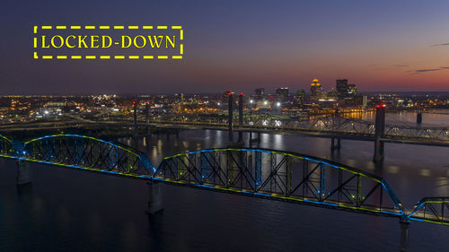 Illuminated bridge over river in city at night