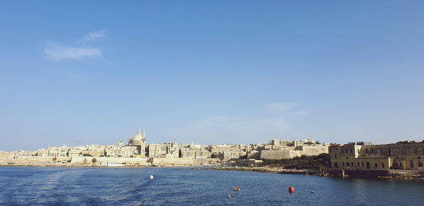 View of buildings by sea against sky