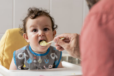 Expressive boy child eating some baby food for lunch.