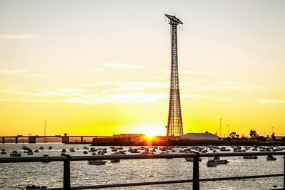 Electricity pylon in city at sunset