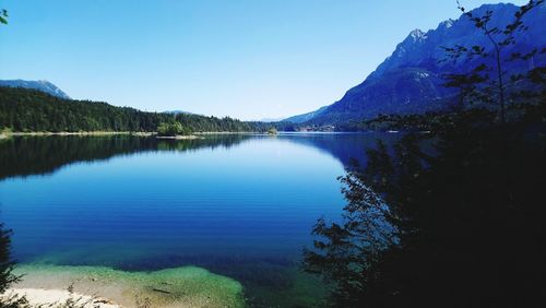 Scenic view of lake and mountains against clear blue sky