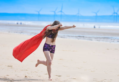 Full length of woman running at beach against sky