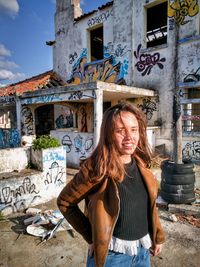 Portrait of smiling woman against graffiti wall