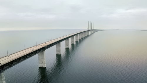 Bridge over calm river against sky