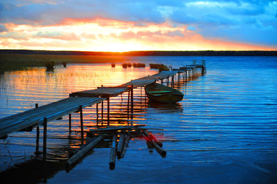 Pier in lake against sky during sunset