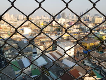 Close-up of cityscape seen through chainlink fence