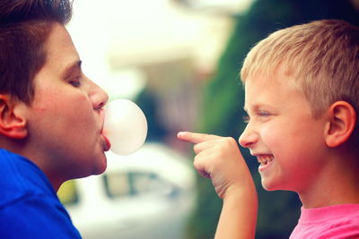 Close-up of boy with brother blowing bubble gum