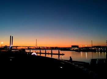 Silhouette of bridge over river at dusk