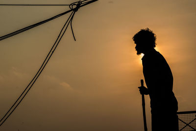 Side view of silhouette man standing against sky during sunset