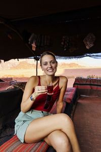 Portrait of young woman sitting in wadi rum desert drinking tea