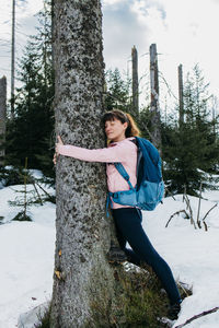 A beautiful girl hugs a tree trunk in the forest with a smile on her face. the concept of love 