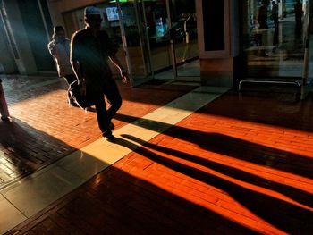 Rear view of man walking on tiled floor in city