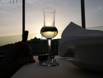 Close-up of hand holding wine glass against sky