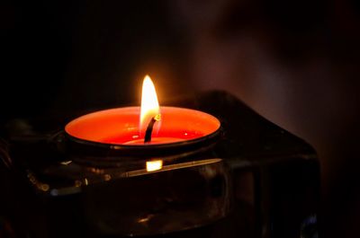 Close-up of lit candle in darkroom