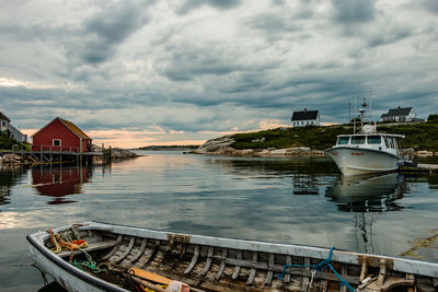 Boats moored in river against cloudy sky at dusk