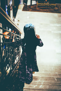 Rear view of woman with umbrella walking on railing