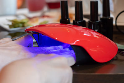Close-up of hand holding red leaf on table
