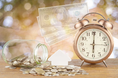 Digital composite image of currency by alarm clock and hands at table