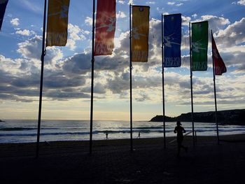 Low angle view of flag at beach against cloudy sky during sunrise