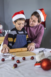 Mother and son making cookies on table at home