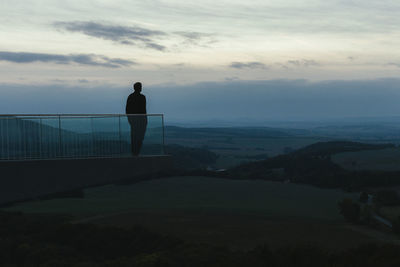 Silhouette man standing on observation point against sky during sunrise