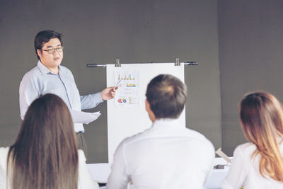 Businessman discussing with colleagues over flipchart at office