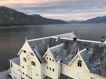 Houses by lake against sky during sunset