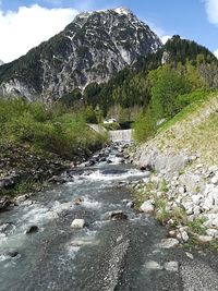 Stream flowing through rocks against sky