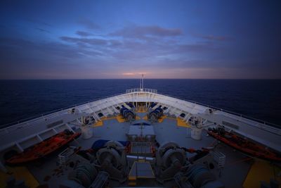 Cropped image of cruise ship in sea against sky at dusk